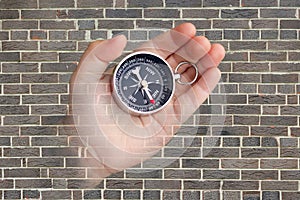 Abstract photo with compass in hand on brick wall background as symbol of tourism