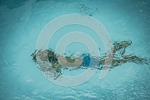 Abstract photo lifestyle, nature background. Unrecognizable person body deep under water, look at surface. Mystery mood