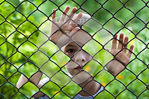 Abstract picture of a little boy behind chain link fence. Photo