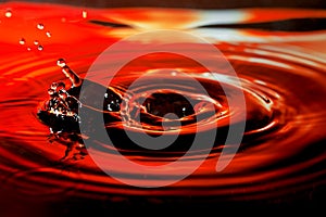 Abstract picture of water drop with splash and ripples on nice red orange background