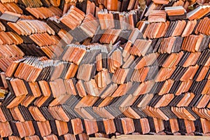 Abstract piles and packs of a new clay ceramic tiles to cover the roof of a Buddhist temple. Stack of new orange roof tiles in the