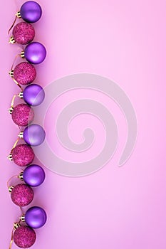 Abstract pink background with christmas purple balls. New year greeting card with shiny spheres. Layout with copy space. Minimal a