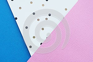 Abstract pink, blue and white paper background with black and brown polka dots.