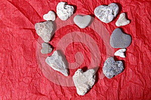 Abstract red background. Many heart-shaped stones are stacked in a heart shape on a red background.
