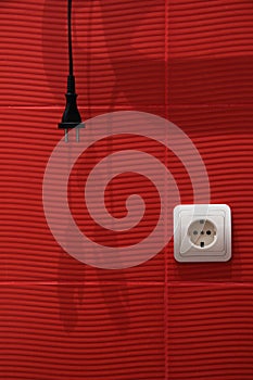 Abstract red background with white socket, black plug, and wire