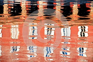 Abstract - reflection on the water of the facade of a red building with its windows