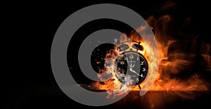 A black alarm clock with large numbers on a dark background surrounded by burning hot particles