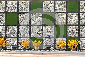 Abstract river pebble stone wall background with green grass frame. Gravel wall background and green grass square shape for backgr