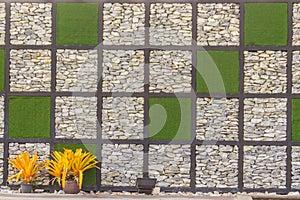 Abstract river pebble stone wall background with green grass frame. Gravel wall background and green grass square shape for backgr