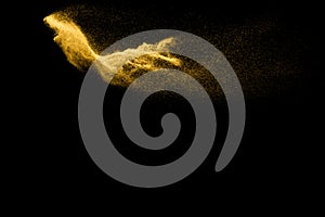 Abstract sand cloud. Golden colored sand splash agianst dark background. Yellow sand fly wave in the air. Sand explode on black