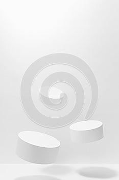 Abstract scene - three round white tilt podiums for cosmetic products mockup, fly in hard light, shadow on white background.