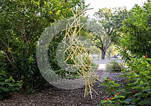 Abstract sculpture with many small yellow pipes tangles and suspended, appearing to defy gravity in Dallas