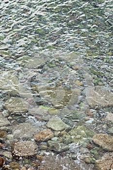 Abstract sea background with water covering stones and pebbles. Vertical orientation