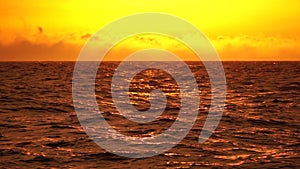 Abstract sea ocean orange warm sunset nature background. Small waves on golden water surface in motion blur with golden