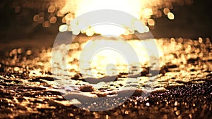 Abstract sea summer ocean sunset nature background. Small waves on golden water surface in motion blur with golden bokeh