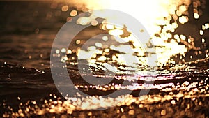 Abstract sea summer ocean sunset nature background. Small waves on golden water surface in motion blur with golden bokeh