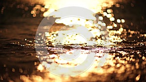 Abstract sea summer ocean sunset nature background. Small waves on golden water surface in motion blur with golden bokeh