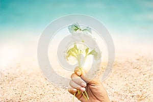 Abstract seaside flowers in hand on sand sea beach summer day