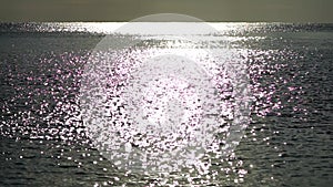 Abstract shining sun reflections on blue surface of sea waves. Bokeh sun glare reflected in water surface. The
