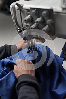 Abstract shot of man sewing blue cloth