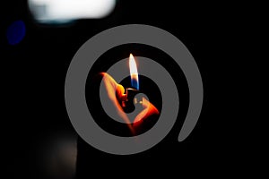 Abstract shot of a person holding a lit lighter in a dark room