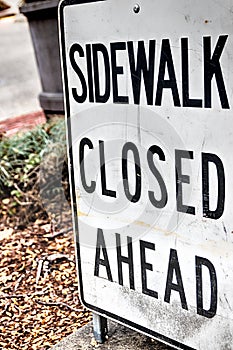 Abstract sidewalk closed ahead sign with plants