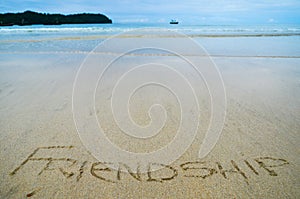 Abstract sign of word friendship written on a sand beach background