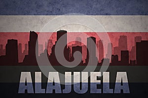 Abstract silhouette of the city with text Alajuela at the vintage costa rican flag