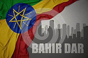 Abstract silhouette of the city with text Bahir Dar near waving colorful national flag of ethiopia on a gray background