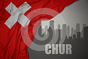 Abstract silhouette of the city with text Chur near waving national flag of switzerland on a gray background