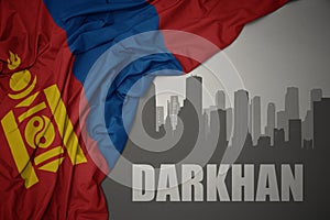 Abstract silhouette of the city with text Darkhan near waving national flag of mongolia on a gray background.3D illustration