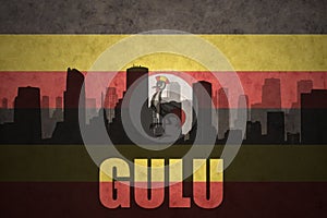 Abstract silhouette of the city with text Gulu at the vintage ugandan flag