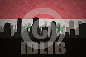 Abstract silhouette of the city with text Idlib at the vintage syrian flag photo