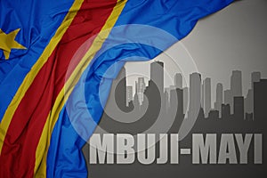 Abstract silhouette of the city with text Mbuji-Mayi near waving colorful national flag of democratic republic of the congo on a