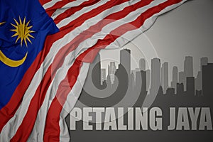 Abstract silhouette of the city with text Petaling Jaya near waving national flag of malaysia on a gray background.3D illustration