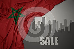 Abstract silhouette of the city with text Sale near waving colorful national flag of morocco on a gray background