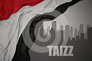 Abstract silhouette of the city with text Taizz near waving national flag of yemen on a gray background