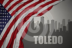 Abstract silhouette of the city with text Toledo near waving national flag of united states of america on a gray background. 3D