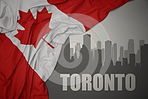 Abstract silhouette of the city with text Toronto near waving national flag of canada on a gray background