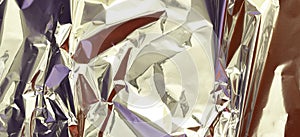 Abstract silver aluminum wrinkled foil multicolored background texture reflecting red and purple light. Silver crumpled