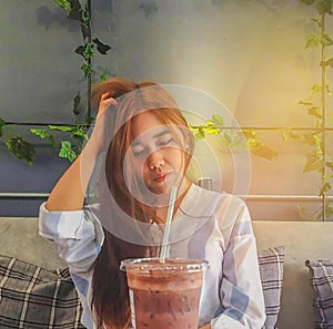 The abstract soft focus of young lady, teenage girl drink the cool coffee in the plastic glass in the room with the beam light, s