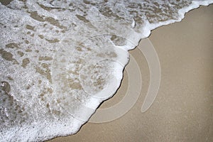 Abstract soft waves on the brown sand beach and white bubbles