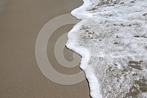 Abstract soft waves on the brown sand beach and white bubbles