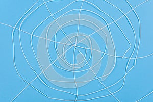 Abstract spiderweb, white threads blue background.