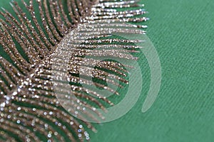 Abstract texture with gold spangles on a green background, similar to a leaf of feather.