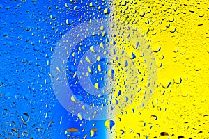Abstract texture. Water drops on glass with blue and yellow background