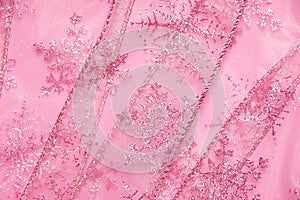 Abstract textured background of pink net ribbon with glitter snowflakes