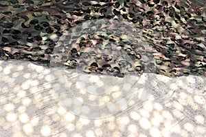 Abstract textured camouflage fabric laid on cement background selectable focus background.