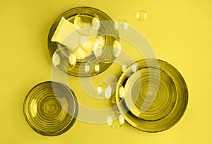 Abstract trendy yellow background with beautiful ceramic plates, cleaning sponge and soap bubbles. Washing dishes concept. Color