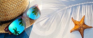 abstract tropical sand beach from above with straw bucket hat and sunglasses, palm trees reflection, summer vacation concept